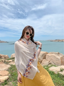 Detail of floral embroidery on lightweight beige summer shawl for beach vacation wear