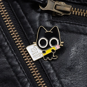 Detail of cartoon black cat enamel pin with Keep Trying sign on a black leather jacket