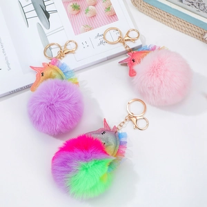 Detailed view of plush unicorn pompom keychains in purple, pink, and rainbow colors