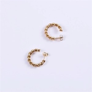 Macro shot of gold-plated twisted C-shaped hoop earrings with detailed braided texture