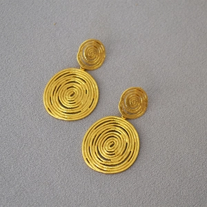 Detailed view of vintage gold-plated spiral disc earrings with textured brass finish
