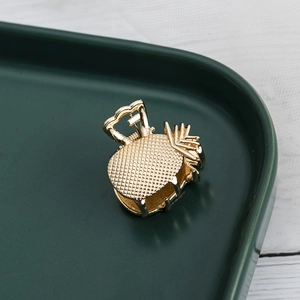 Detail showing gold metal pineapple hair claw clip with textured leaf pattern details