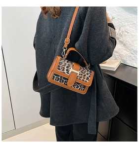 Leopard print handbag with brown trim and gold H-buckle shown on a model's shoulder