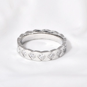 Macro shot of silver diamond-set rhombus pattern ring on white textured fabric