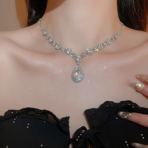 Close-up of a luxury silver-tone tennis necklace with a large pear-cut halo pendant