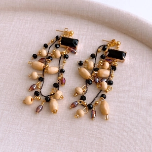 Detail of vintage earrings with wood beads, black gemstones and bohemian tassels