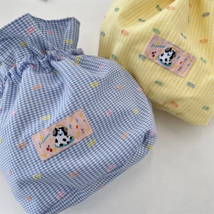 Detail of blue and yellow plaid drawstring pouches with cartoon puppy embroidery