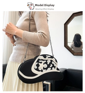 Detail view of denim hat shaped crossbody bag with star pattern and chain strap on model