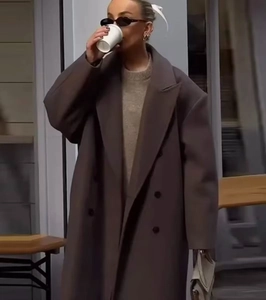 Detail of an oversized double-breasted wool coat in dark brown for a chic urban street look