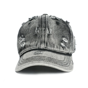Close-up of washed distressed denim baseball cap with vintage frayed holes and texture