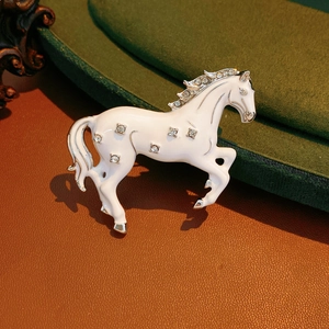 Detailed macro shot of a white enamel horse brooch with sparkling crystal accents