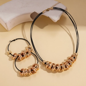 Detail view of multi-layer black cord necklace with gold geometric circular rings