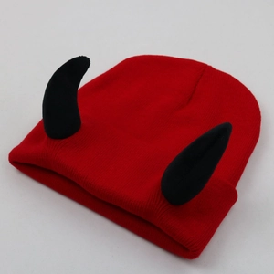 Detail view of a red knitted beanie with black devil horns and textured stitching
