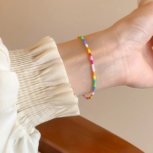 Close-up of colorful beaded star bracelet with gold accents worn on a female wrist