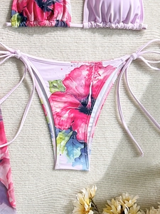 Detail of floral bikini bottoms with side ties on a soft knitted texture background