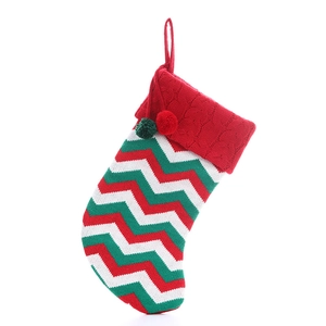 Knitted Christmas stocking with red, green and white wavy patterns and hanging pom poms