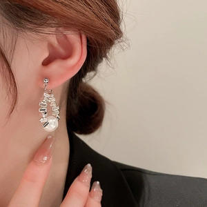 Detail shot of a model wearing the irregular silver metal and pearl drop earring