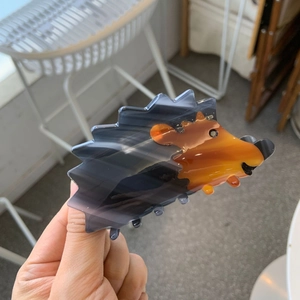 Close-up of a hedgehog shaped acetate hair claw clip in purple and amber gradient finish