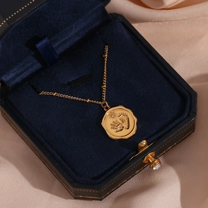 Détail macro du pendentif pièce dorée avec empreintes de bébé sur velours bleu marine