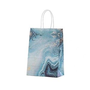 Blue marble gift bag with gold glitter accents and white paper twist handles on white base