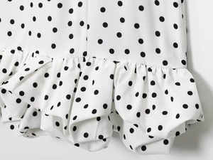Détail d'une robe blanche à pois avec ourlet à volants élégant et texture textile lisse