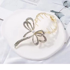 Close-up of golden metal butterfly hair claw with rhinestones and center pearl detail