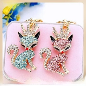 Detailed close-up of blue and pink rhinestone fox pendants with golden crowns