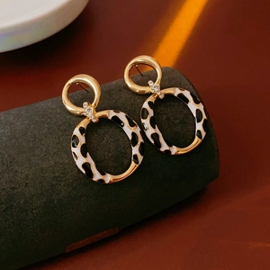 Detail of vintage gold earrings featuring cow print enamel rings and sparkling zircon accents