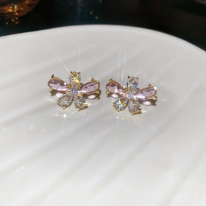 Macro shot of gold floral earrings with pink and clear cubic zirconia on shell