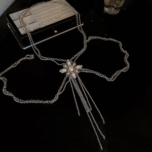 Detail of silver body chain featuring a pearl and rhinestone cross pendant with tassels