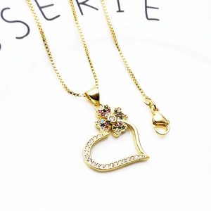Macro shot of gold heart pendant with colorful gemstones and zirconia on box chain