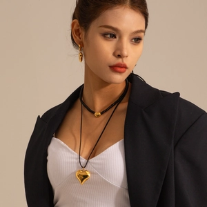 Detail of layered gold heart necklaces and teardrop earrings on a female model