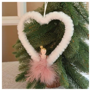 Detail of plush heart angel ornament with pink feathers hanging on a Christmas tree branch