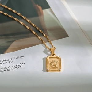 Detail of gold angel pendant with relief design and small crystals on a fine chain