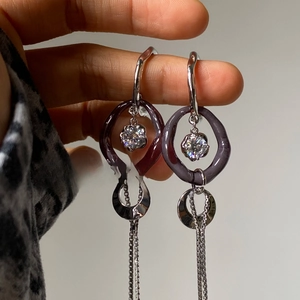 Detail of silver long tassel earrings with purple resin circle and sparkling zircon