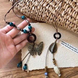 Ethnic bohemian pendant necklace with butterfly and leaf motifs on wax cord chain