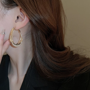 Detail of gold oval mesh hoop earrings with pavé stones shown on model
