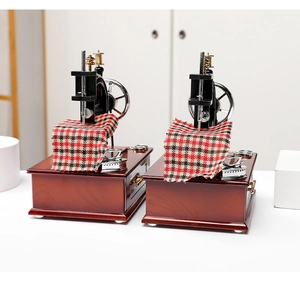 Detail of vintage sewing machine music box with metal needles and red plaid fabric