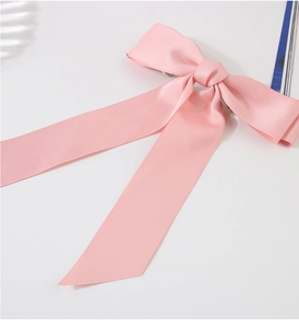 Detail view of a pink satin oversized bow hair clip with silk gloss on white background