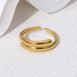 Detailaufnahme eines doppellagigen goldenen Rings mit geometrischen Linien auf weißem Stein