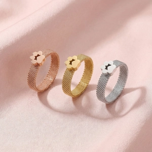 Detailed view of three mesh band rings in rose gold, gold, and silver on pink silk fabric