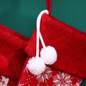 Pair of red knitted Christmas stockings with white snowflake patterns and fuzzy pom-poms