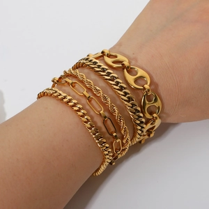 Detail of five 18K gold plated stainless steel bracelets layered on a wrist