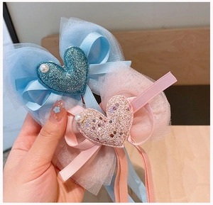 Dettaglio di fermagli per capelli in pizzo con cuori glitterati e perle per bambine