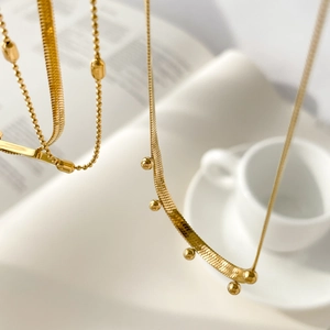 Detailed macro view of gold snake chain with metal beads and classic bead necklace set
