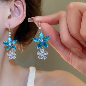 Gros plan de boucles d'oreilles fleurs avec cristaux bleus et clairs sur un mannequin