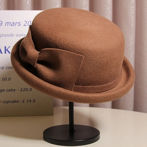 Detail of wool felt cloche hat with ribbon bow and elegant curled brim in dark brown