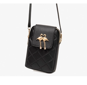 Detail of black quilted mini phone bag featuring a gold flamingo heart-shaped clasp