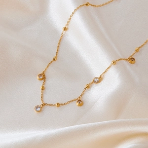 Detail of gold necklace with round zircon stones on elegant beige silk fabric