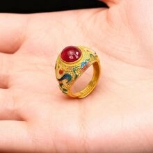Makrodetail eines goldenen Rings mit rotem Edelstein und buntem Emaille-Muster